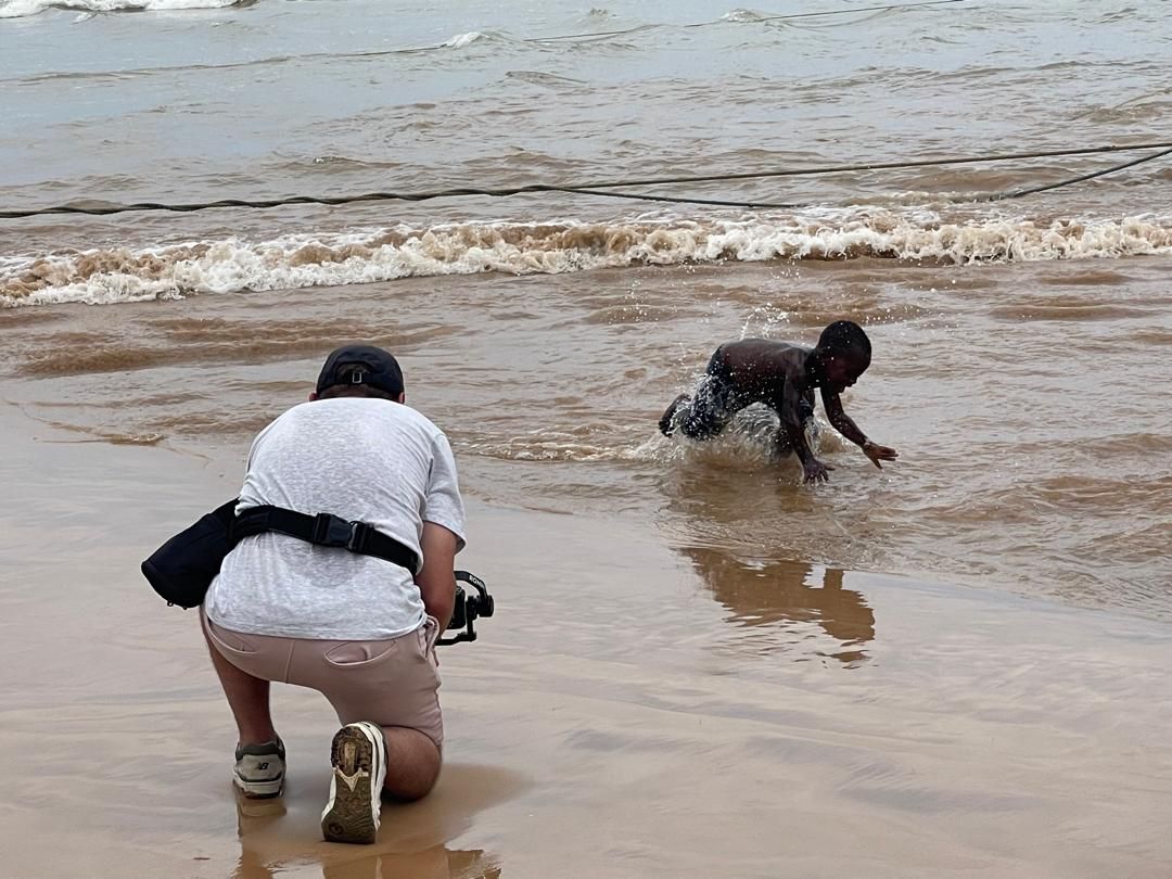 Crew filming children playing in the surf at Dixcove