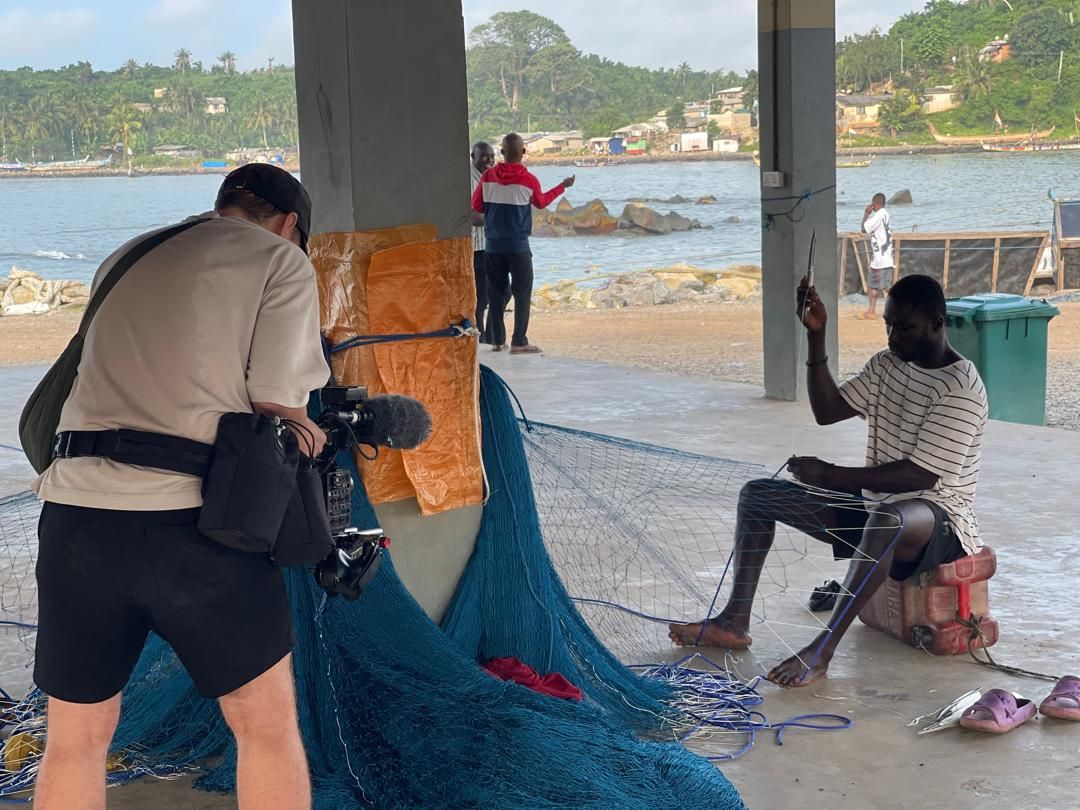 Crew filming a fisherman repairing nets on the Dixcove coastline